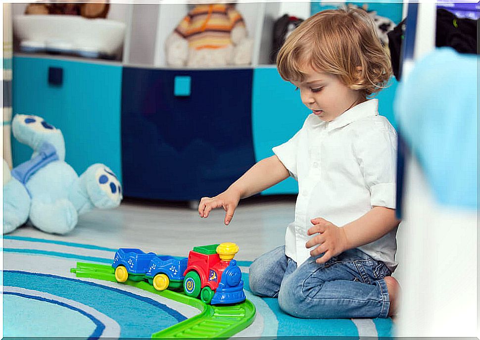 Two year old boy playing with a three sitting on the floor.