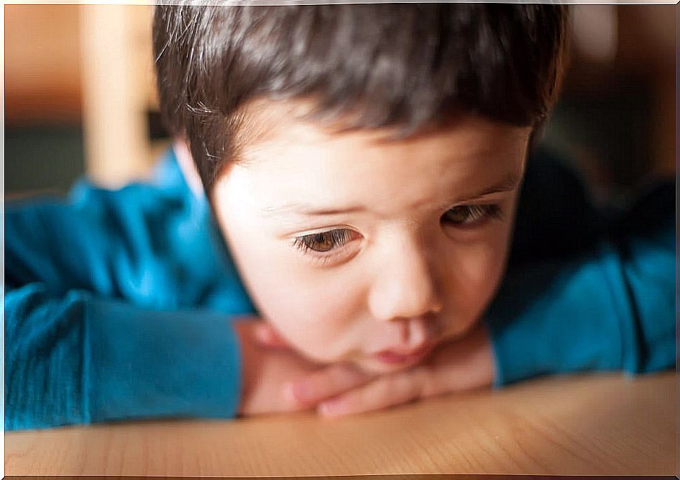 Sad and pensive child leaning on the table.