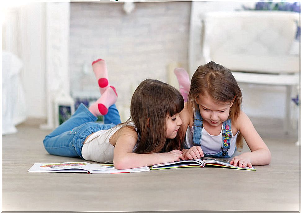 Girls reading bilingual children's books on the floor to learn English.