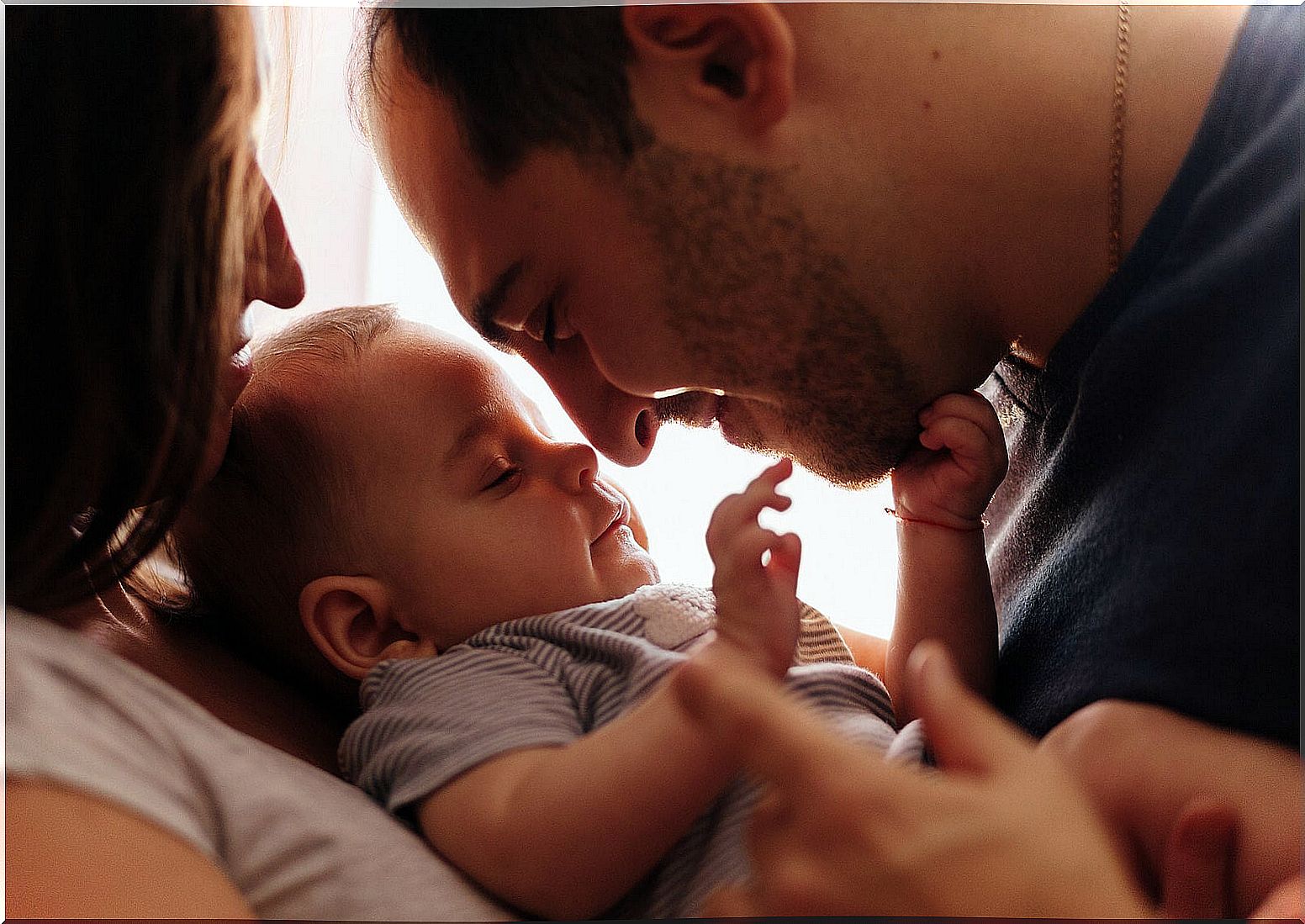 Parents hugging their baby to bond and connect with him.