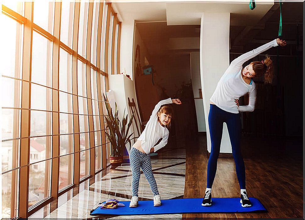 Mother and daughter exercising at home to cope with quarantine.