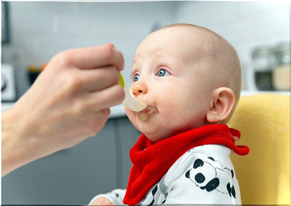 Baby eating fruit porridge for a snack.