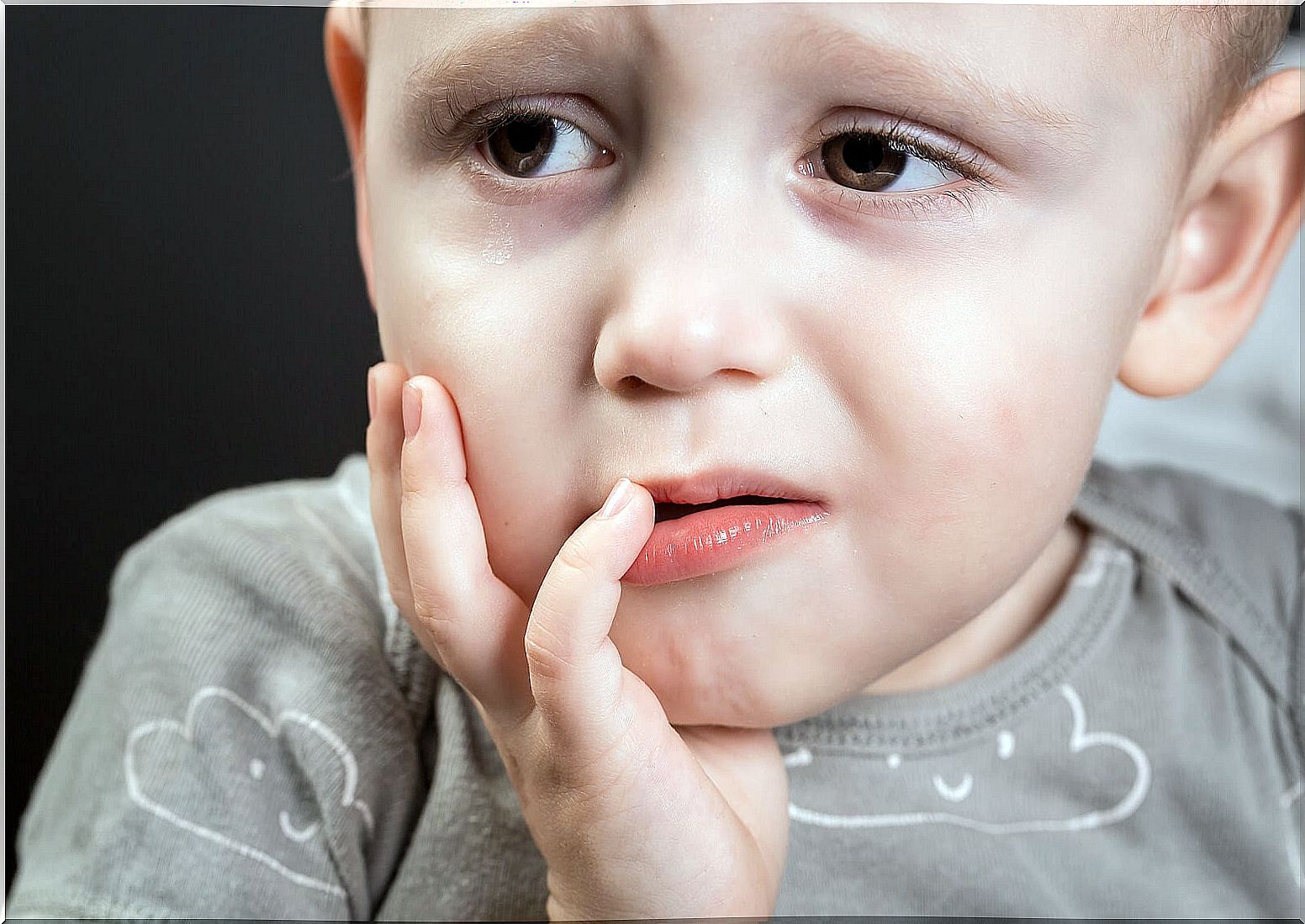 Child with pain in the mouth and a black tooth.