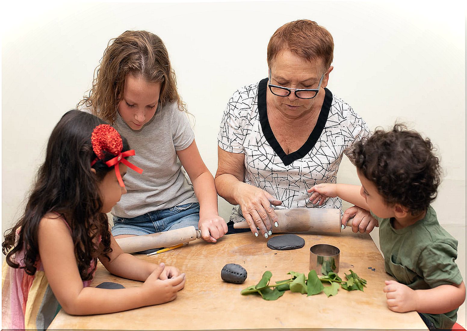 Grandmother making clay figures with her grandchildren.