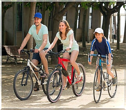 Parents friends of their son riding a bicycle with him.