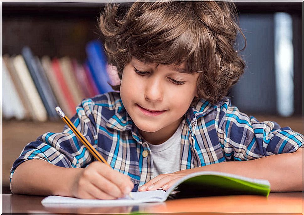 Child writing new words in a notebook to detect possible symptoms of dysgraphia.