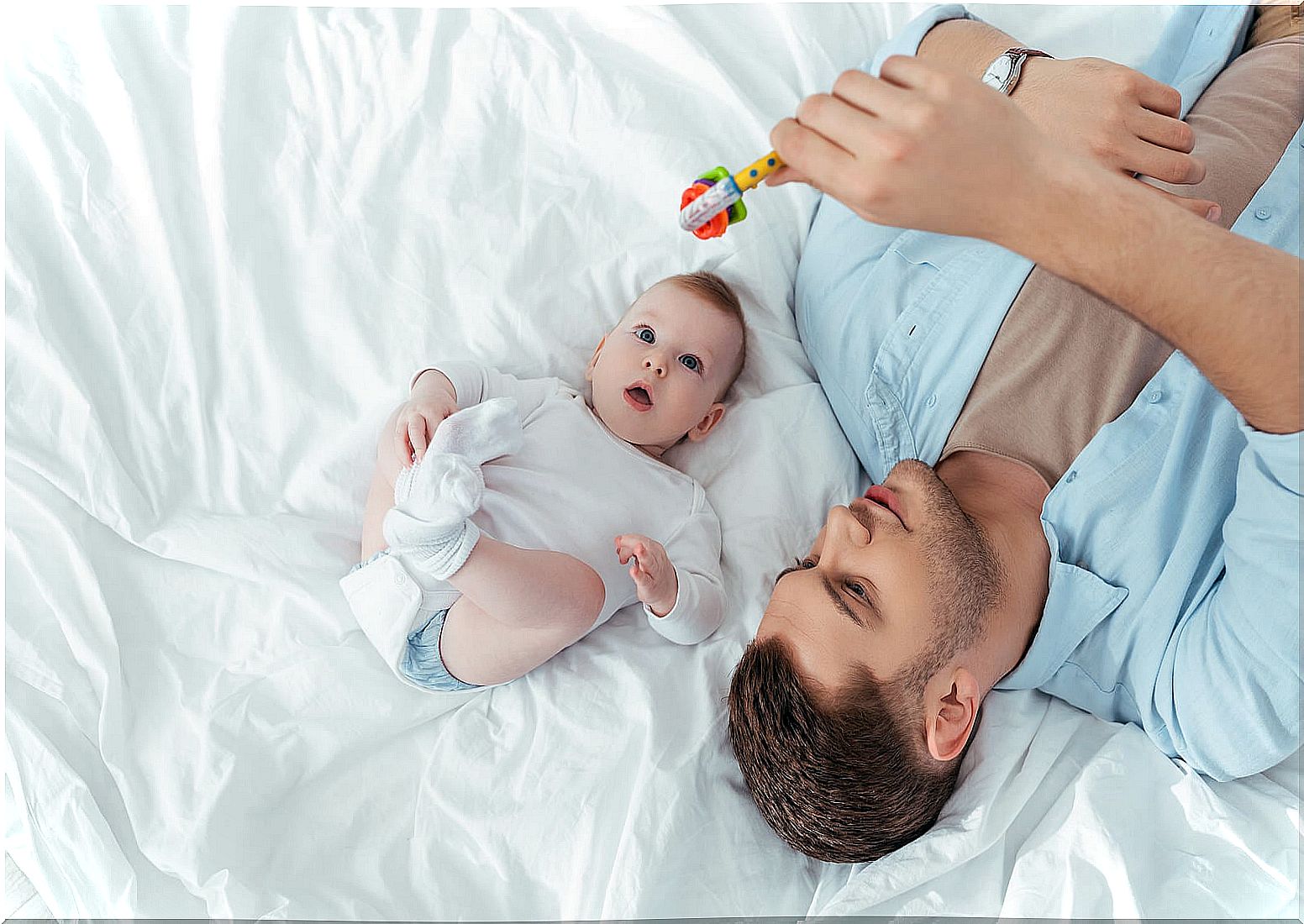 Father playing with his baby with a rattle.