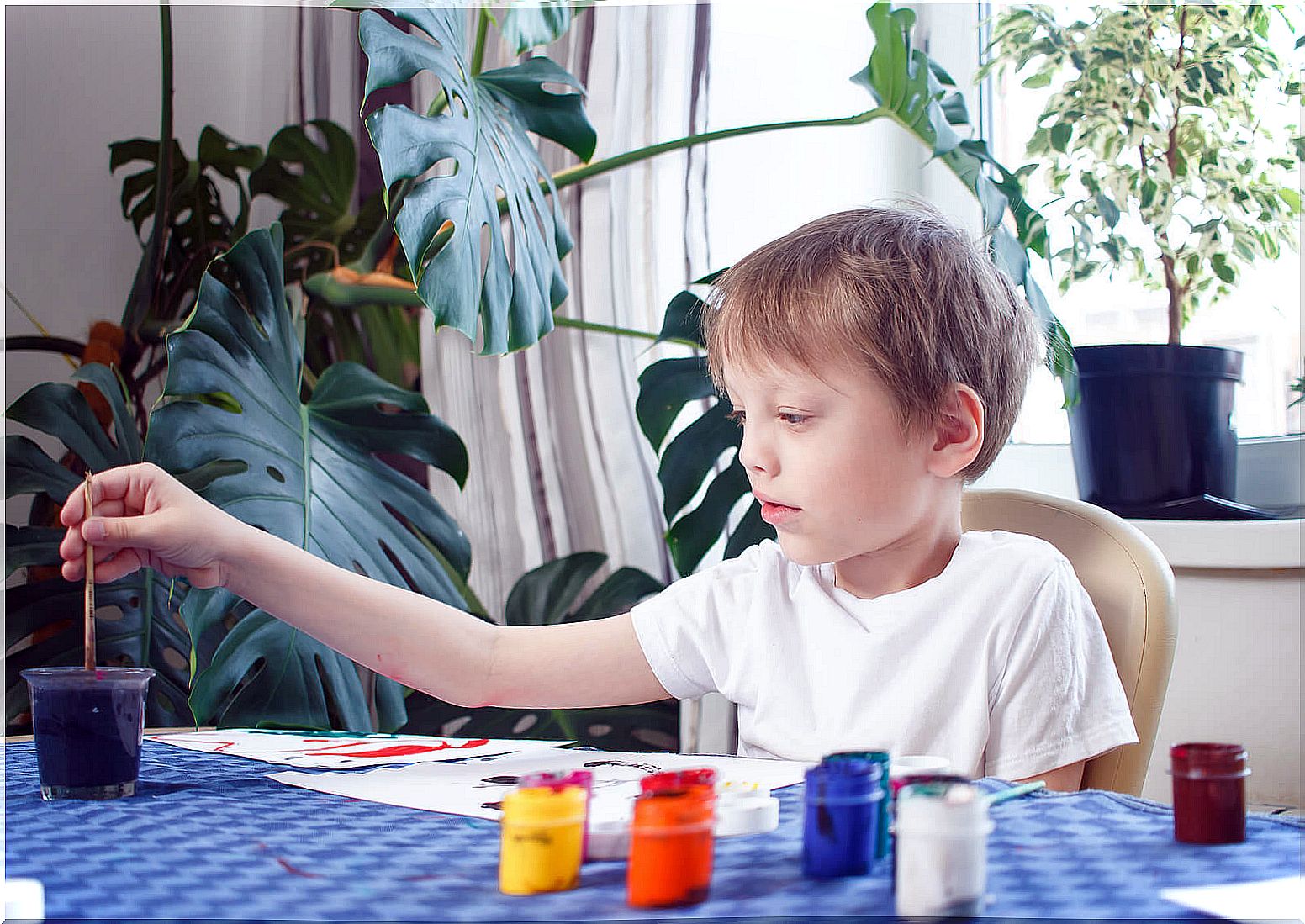 Child painting and drawing with tempera.