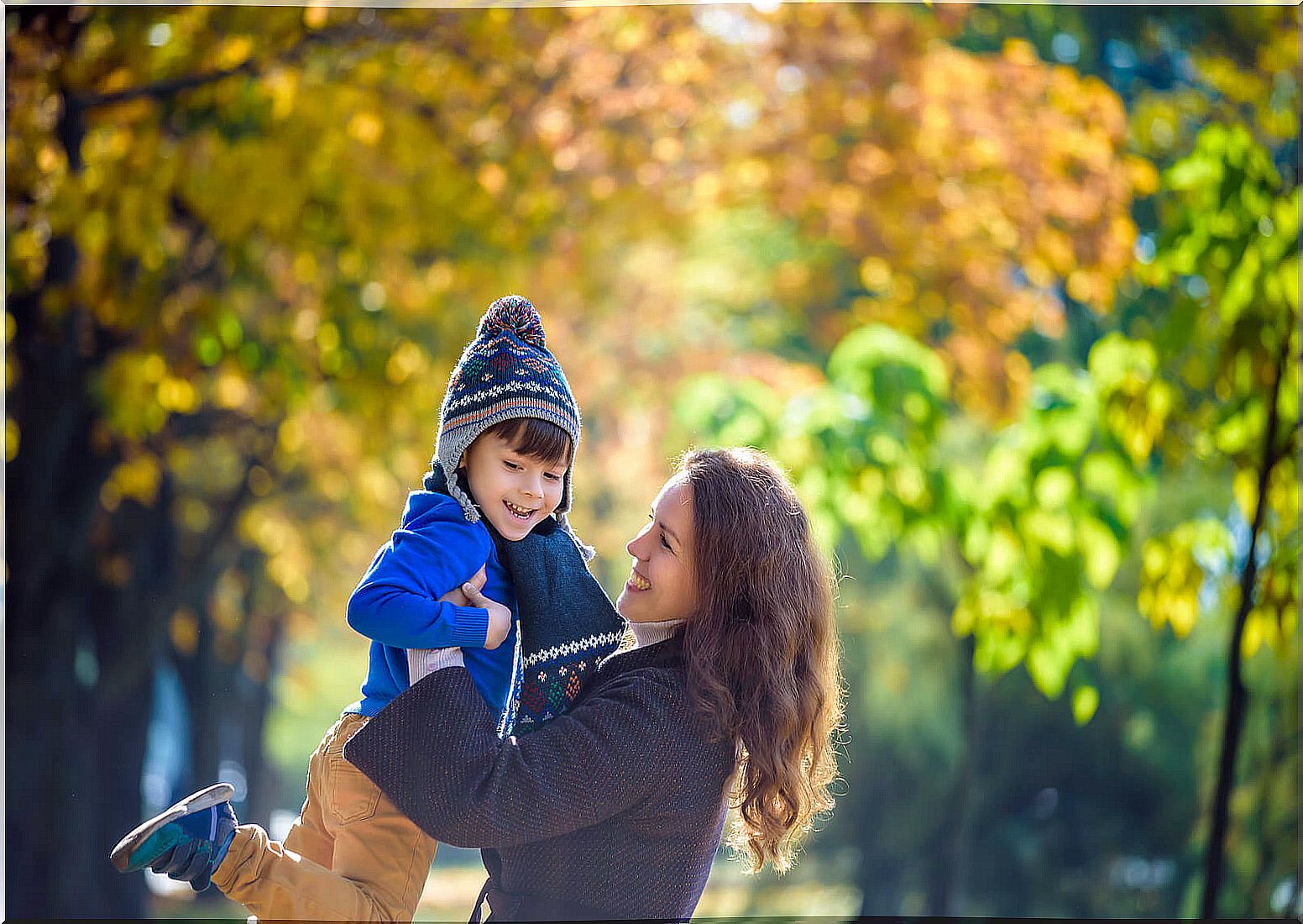 Mother playing with her son in a park in autumn.