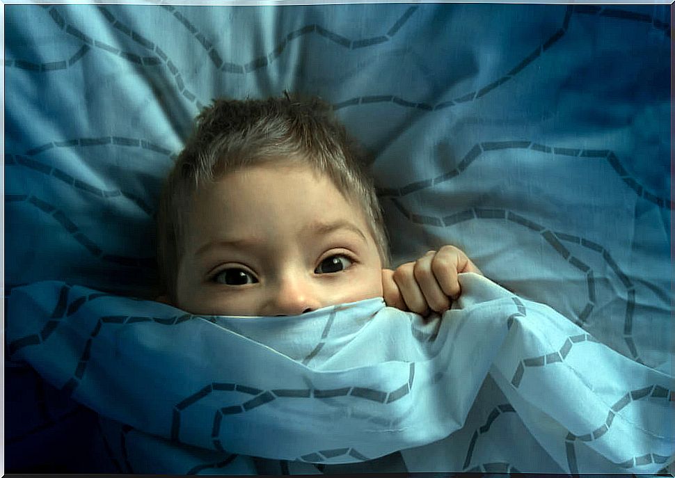 Scared child in bed suffering childhood regression during the pandemic.