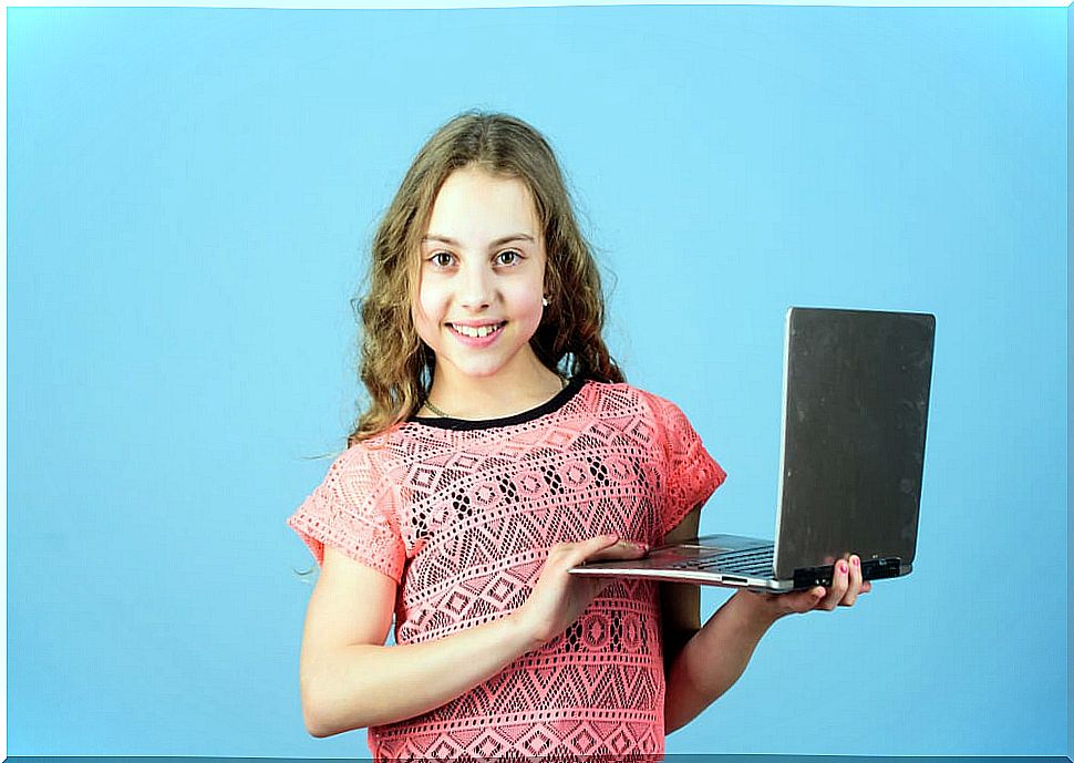 Little girl with the computer in her hands ready for her classes at the online English school.