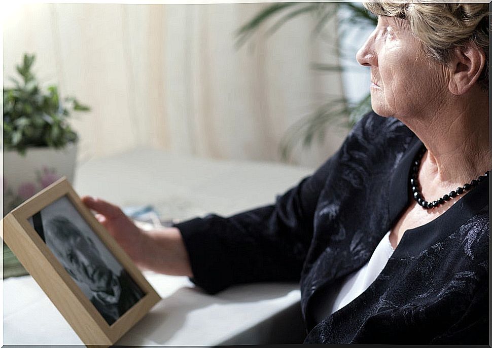 Widowed woman with the photo of her deceased husband in her hand.