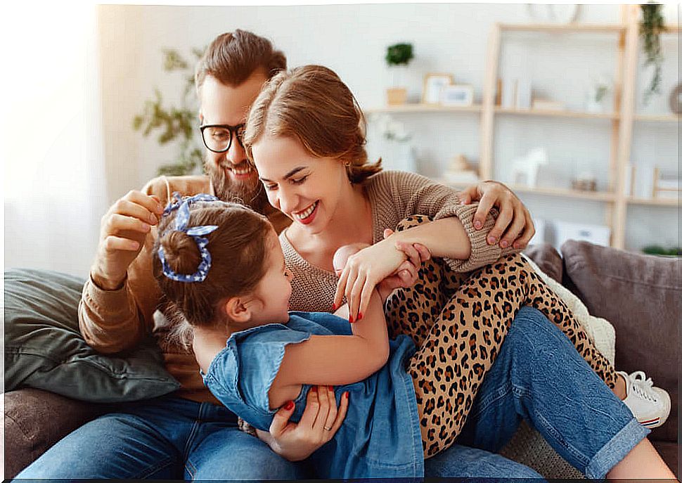 Parents tickling their daughter on the couch.